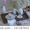 Coffee with milk in a porcelain cup, a milk jug and wildflowers on a wooden tray 141187691