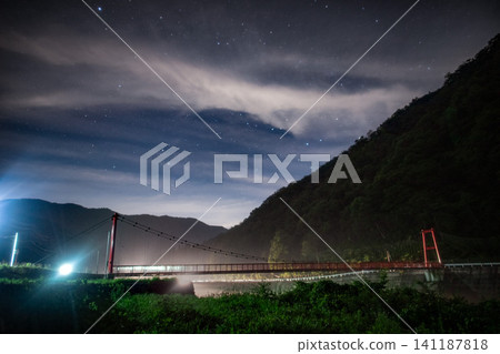 一座紅色的橋樑漂浮在漆黑的夜空中，閃耀著銀河的神秘光芒。 141187818