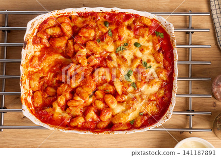 Baked gnocchi with tomato sauce, melted cheese and basil in ceramic dish viewed from above Baked gnocchi with tomato sauce, melted cheese and basil in ceramic dish viewed from above 141187891