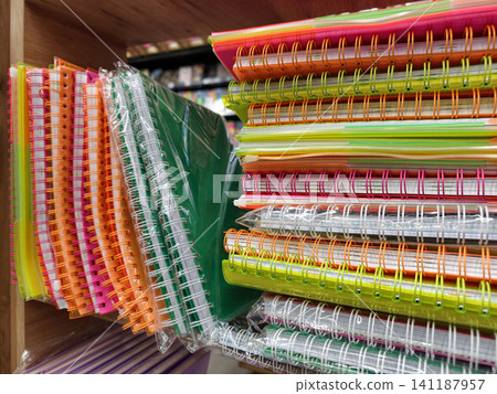 Variety of softcover spiral notebooks lined up on stationery shop shelf Variety of softcover spiral notebooks lined up on stationery shop shelf 141187957