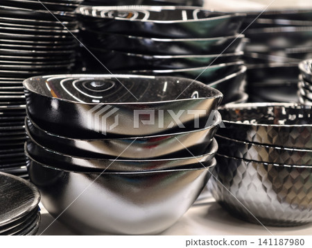Black matte salad bowls stacked evenly on store shelving with classic rounded design for everyday use Black matte salad bowls stacked evenly on store shelving with classic rounded design for everyday use 141187980