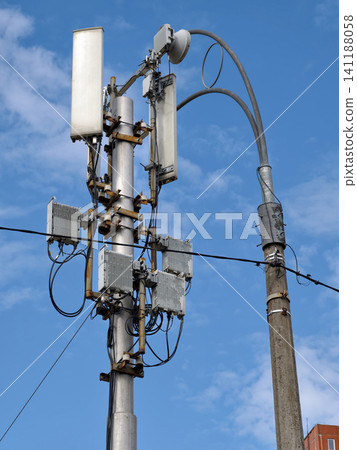 A simple mobile network tower placed on a low pole near a roadside lamp 141188058