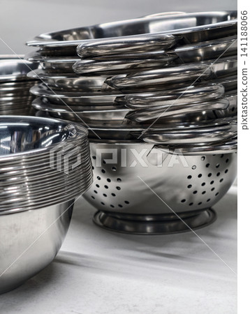 Stacked stainless steel bowls and colanders displayed on supermarket retail shelves, showcasing durable kitchenware with polished surfaces designed for everyday cooking and food preparation Stacked stainless steel bowls and colanders displayed on supermarket retail shelves, showcasing durable kitchenware with polished surfaces designed for everyday cooking and food preparation 141188066