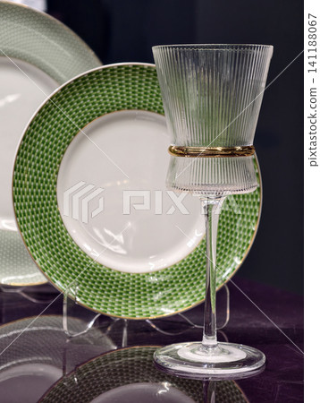 Elegant wine glass shining with green plates softly blurred behind on a luxury table 141188067