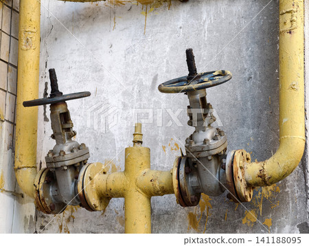 Gas control valves connected to yellow pipes on the outer wall of a residential property with urban utility communication network Gas control valves connected to yellow pipes on the outer wall of a residential property with urban utility communication network 141188095
