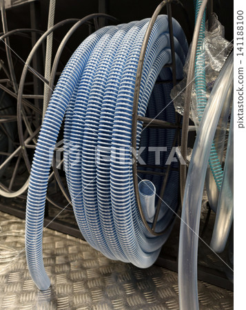 Blue corrugated hose rolled into a storage coil is presented on retail shelves in a building supplies supermarket Blue corrugated hose rolled into a storage coil is presented on retail shelves in a building supplies supermarket 141188100