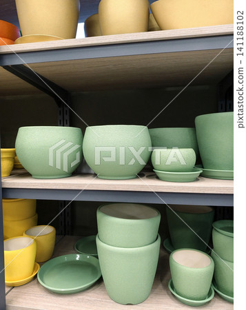 Blue ceramic planters with saucers in assorted sizes arranged on shelves in a garden supply store Blue ceramic planters with saucers in assorted sizes arranged on shelves in a garden supply store 141188102