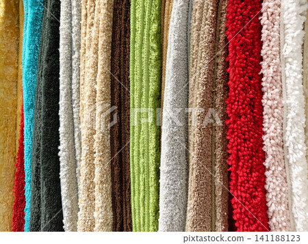 Multicolored carpets neatly displayed on a store counter for customers to browse Multicolored carpets neatly displayed on a store counter for customers to browse 141188123