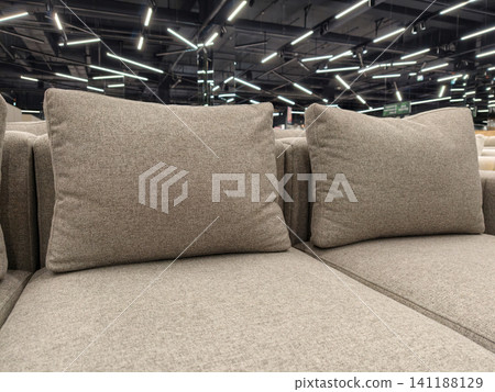 A soft gray sofa featuring large cushions, for sale in a furniture store 141188129