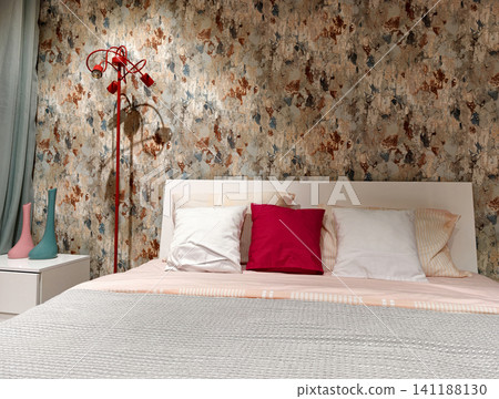 Room interior showing a bed with pillows and a blanket, a lamp next to the bed and wallpaper on the wall, items presented as samples for sale in a supermarket Room interior showing a bed with pillows and a blanket, a lamp next to the bed and wallpaper on the wall, items presented as samples for sale in a supermarket 141188130