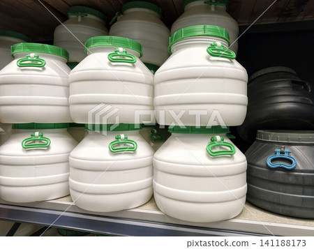 Rows of white and black barrels with lids are displayed on shelves in a building hypermarket, offering practical storage solutions Rows of white and black barrels with lids are displayed on shelves in a building hypermarket, offering practical storage solutions 141188173