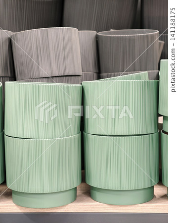 Green and gray plastic plant pots arranged neatly in a flower shop ready for customers searching for gardening supplies 141188175