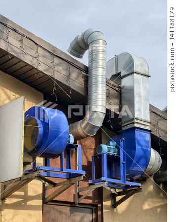 Industrial building rooftop featuring exterior ventilation fan with electric motor for efficient air exhaust Industrial building rooftop featuring exterior ventilation fan with electric motor for efficient air exhaust 141188179