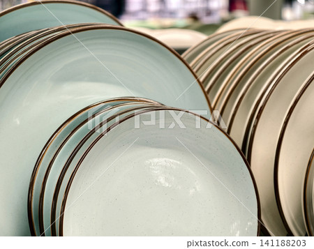 Beautiful light blue ceramic plates of different sizes on supermarket shelves, close up of kitchen tableware Beautiful light blue ceramic plates of different sizes on supermarket shelves, close up of kitchen tableware 141188203