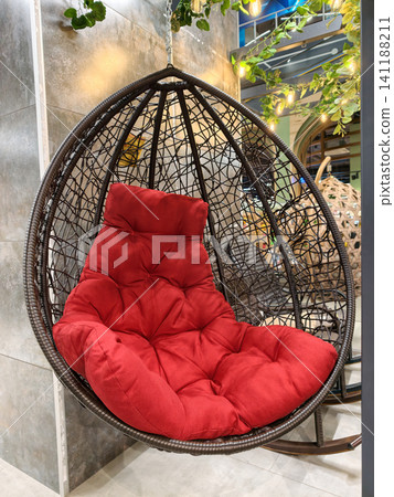 Suspended basket chair with large soft cushion mattress displayed in supermarket offers comfortable lounging and modern home relaxation furniture solution Suspended basket chair with large soft cushion mattress displayed in supermarket offers comfortable lounging and modern home relaxation furniture solution 141188211