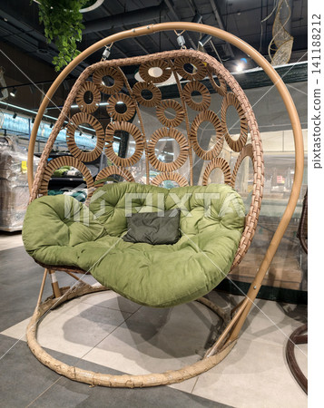 Stylish suspended basket chair with large soft cushion mattress in supermarket store display emphasizes comfortable modern lounging furniture solution Stylish suspended basket chair with large soft cushion mattress in supermarket store display emphasizes comfortable modern lounging furniture solution 141188212