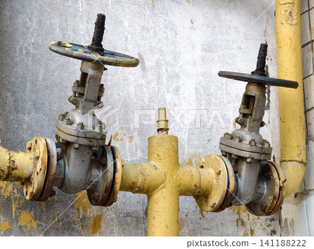 Gas pipeline control valves installed on the exterior side of residential housing with yellow utility pipe infrastructure detail Gas pipeline control valves installed on the exterior side of residential housing with yellow utility pipe infrastructure detail 141188222