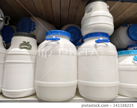 A display of large white plastic barrels on shelves in a home improvement store, ready for purchase 141188225