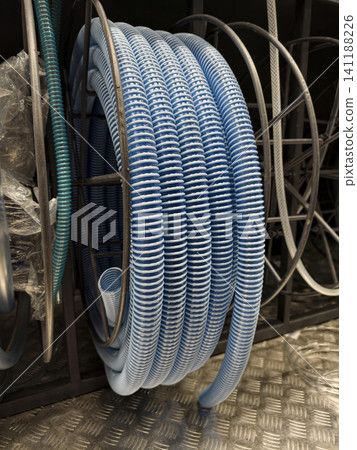 Blue corrugated hose wound into a neat coil is available on retail shelves in a construction supply department Blue corrugated hose wound into a neat coil is available on retail shelves in a construction supply department 141188226