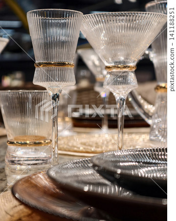 Elegant crystal wine glasses reflecting light on a deluxe table with decorative touches 141188251