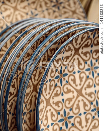 Beautiful patterned ceramic plates with blue rim on shelves in supermarket, close up of ceramic dishware for household and kitchen use Beautiful patterned ceramic plates with blue rim on shelves in supermarket, close up of ceramic dishware for household and kitchen use 141188258