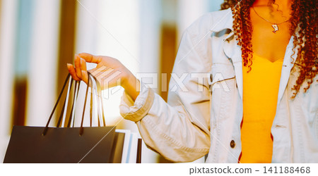 Young woman with shopping bags walking on street. Sale, shopping and happy people concept. 141188468