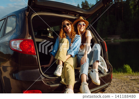 Two Young woman takes a selfie in the car during a road trip. Lifestyle, travel, tourism, nature. Two Young woman takes a selfie in the car during a road trip. Lifestyle, travel, tourism, nature. 141188480