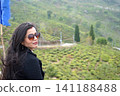 Young indian woman wearing sunglasses enjoying scenic view at a tea garden in Darjeeling 141188488