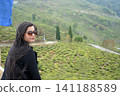 Beautiful indian woman with sunglasses looking away at tea plantation in Darjeeling 141188589