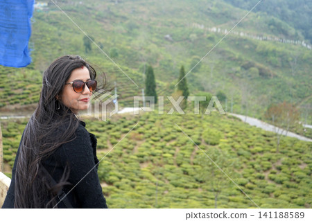 Beautiful indian woman with sunglasses looking away at tea plantation in Darjeeling Beautiful indian woman with sunglasses looking away at tea plantation in Darjeeling 141188589