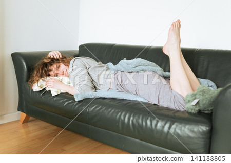 young red-haired woman relaxing on leather sofa young red-haired woman relaxing on leather sofa 141188805