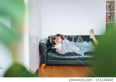 young red-haired woman relaxing on leather sofa young red-haired woman relaxing on leather sofa 141188808