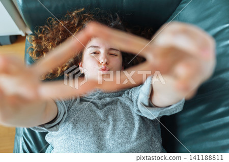 young red-haired woman relaxing on leather sofa young red-haired woman relaxing on leather sofa 141188811