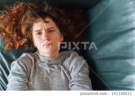 young red-haired woman relaxing on leather sofa young red-haired woman relaxing on leather sofa 141188815