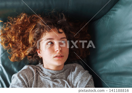 young red-haired woman relaxing on leather sofa young red-haired woman relaxing on leather sofa 141188816