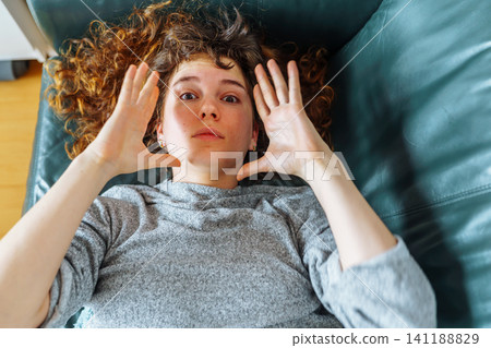 young red-haired woman relaxing on leather sofa young red-haired woman relaxing on leather sofa 141188829
