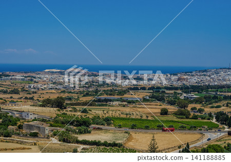 Panoramic view of Malta countryside with fields, town, Mosta Rotunda dome and Mediterranean sea under clear blue sky Panoramic view of Malta countryside with fields, town, Mosta Rotunda dome and Mediterranean sea under clear blue sky 141188885