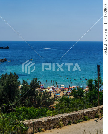 Scenic Mediterranean bay view with sandy beach, colorful umbrellas and turquoise sea framed by pine trees, Malta summer Scenic Mediterranean bay view with sandy beach, colorful umbrellas and turquoise sea framed by pine trees, Malta summer 141188900