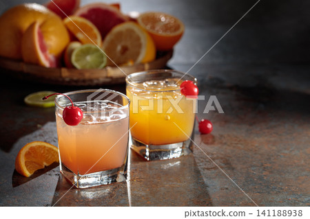 Cocktails with ice, grapefruit juice, and orange juice garnished with maraschino cherry. Cocktails with ice, grapefruit juice, and orange juice garnished with maraschino cherry. 141188938