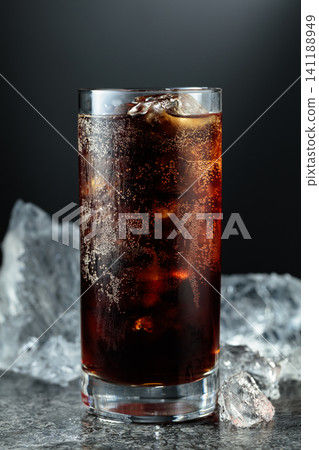 Cola with ice in misted glass on a black stone table. Cola with ice in misted glass on a black stone table. 141188949