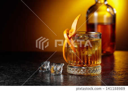 Old-fashioned cocktail in a fogged up glass on a black stone table. Old-fashioned cocktail in a fogged up glass on a black stone table. 141188989