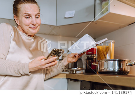 middle-aged woman prepares a recipe for lunch in her home kitchen 141189174