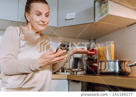 middle-aged woman prepares a recipe for lunch in her home kitchen middle-aged woman prepares a recipe for lunch in her home kitchen 141189177