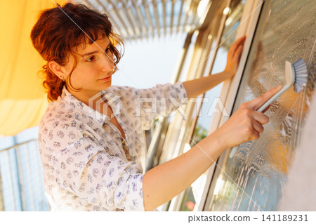 young woman washes windows on terrace young woman washes windows on terrace 141189231