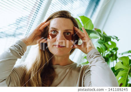middle-aged woman with long blonde hair and patches under her eyes middle-aged woman with long blonde hair and patches under her eyes 141189245