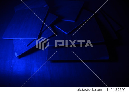 Stack of blank paper sheets glowing under blue ultraviolet light with stationery Stack of blank paper sheets glowing under blue ultraviolet light with stationery 141189291