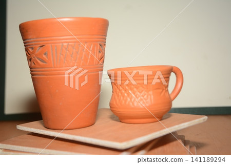 Two traditional decorative terra cotta clay cups on stacked ceramic tiles Two traditional decorative terra cotta clay cups on stacked ceramic tiles 141189294