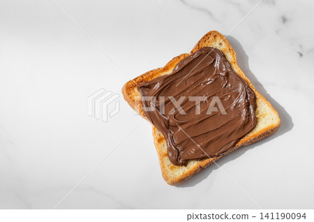 Toasted bread with chocolate cream on a marble background close up. Toasted bread with chocolate cream on a marble background close up. 141190094