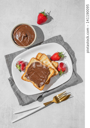 Toasted bread with chocolate cream and strawberry on a plate on a concrete background Toasted bread with chocolate cream and strawberry on a plate on a concrete background 141190095