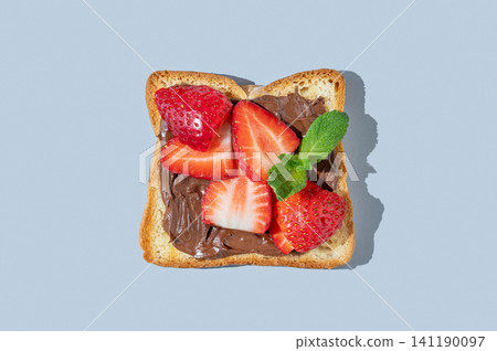 Toasted slice with chocolate cream and strawberries on a blue isolated background Toasted slice with chocolate cream and strawberries on a blue isolated background 141190097